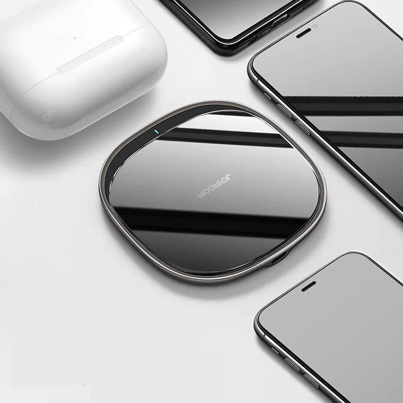 Square black 15W wireless phone charger with a glass top and zinc alloy frame on a desk.