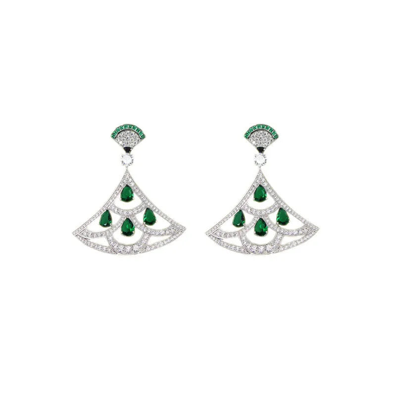 Silver fan-shaped earring with gold-plated inlay of artificial gems, on a plain background