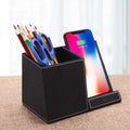 Black leather pen holder with integrated wireless phone charging pad on a desk
