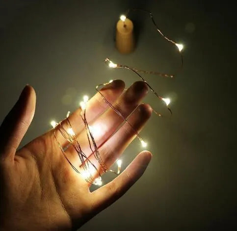 Copper wire LED string lights inserted into wine bottle with warm white illumination