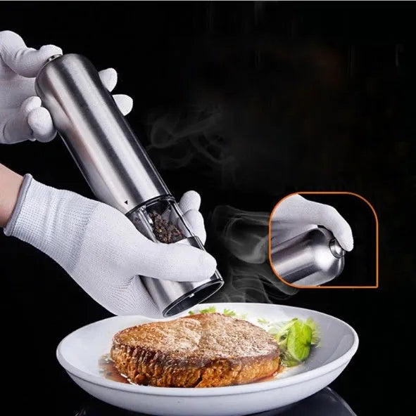 Stainless steel electric spice grinder with ceramic burrs on a kitchen counter.