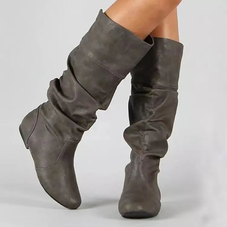 Women's black slip-on flat boots with round toe and high cylinder shaft on neutral background