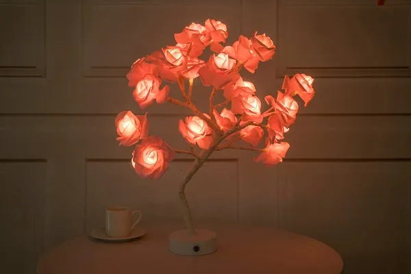 White and red rose shaped LED table lamp with bonsai tree base on a wooden table.