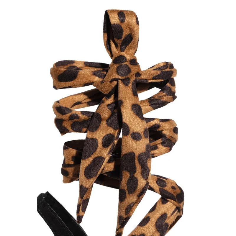 Light brown leopard print women's high heels with cross-straps and a tall stiletto heel.