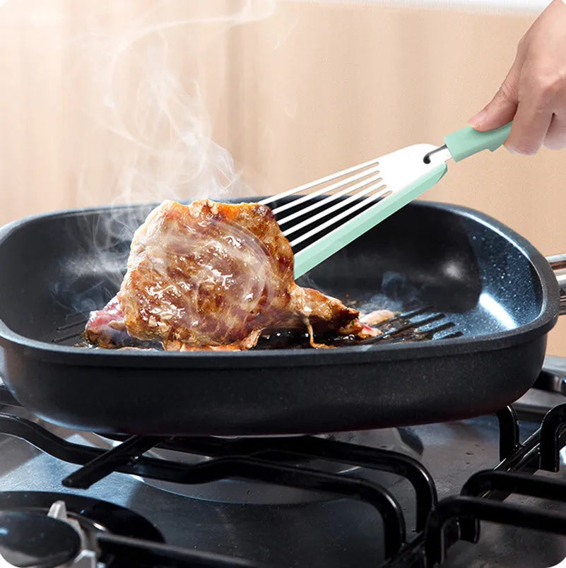 Green silicone fish spatula with 1mm thin slotter blade and hanging hole on a kitchen counter
