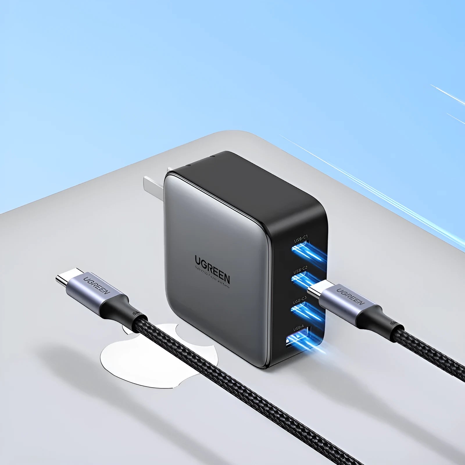 100W Gallium Nitride fast wall charger with USB-C port on a desk next to a laptop.