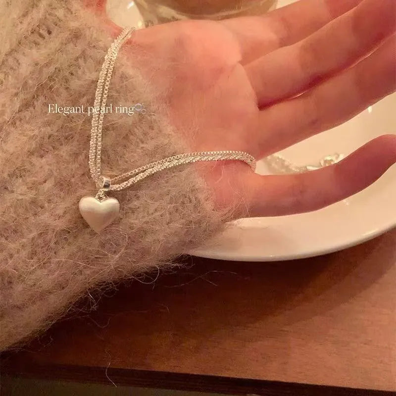 Women's double-layer brushed heart pendant necklace on a regular chain, silver tone.
