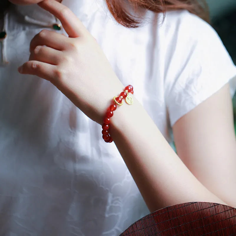 Close-up of a woven red agate bracelet showing bead detail and blessing card.