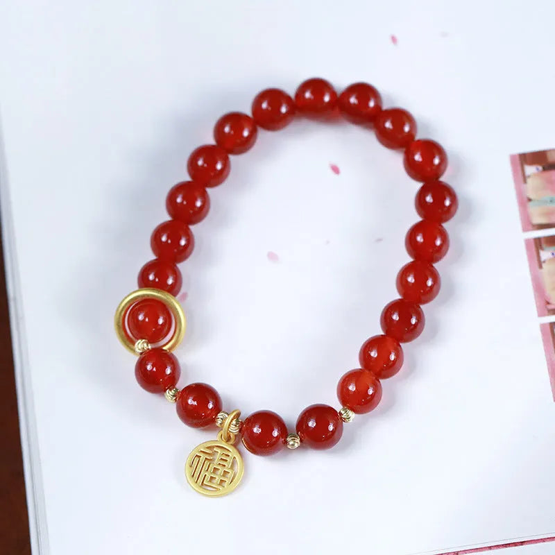 Close-up of a woven red agate bracelet showing bead detail and blessing card.