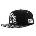 Black cotton baseball cap with white letter embroidery on the front, showing adjustable strap.