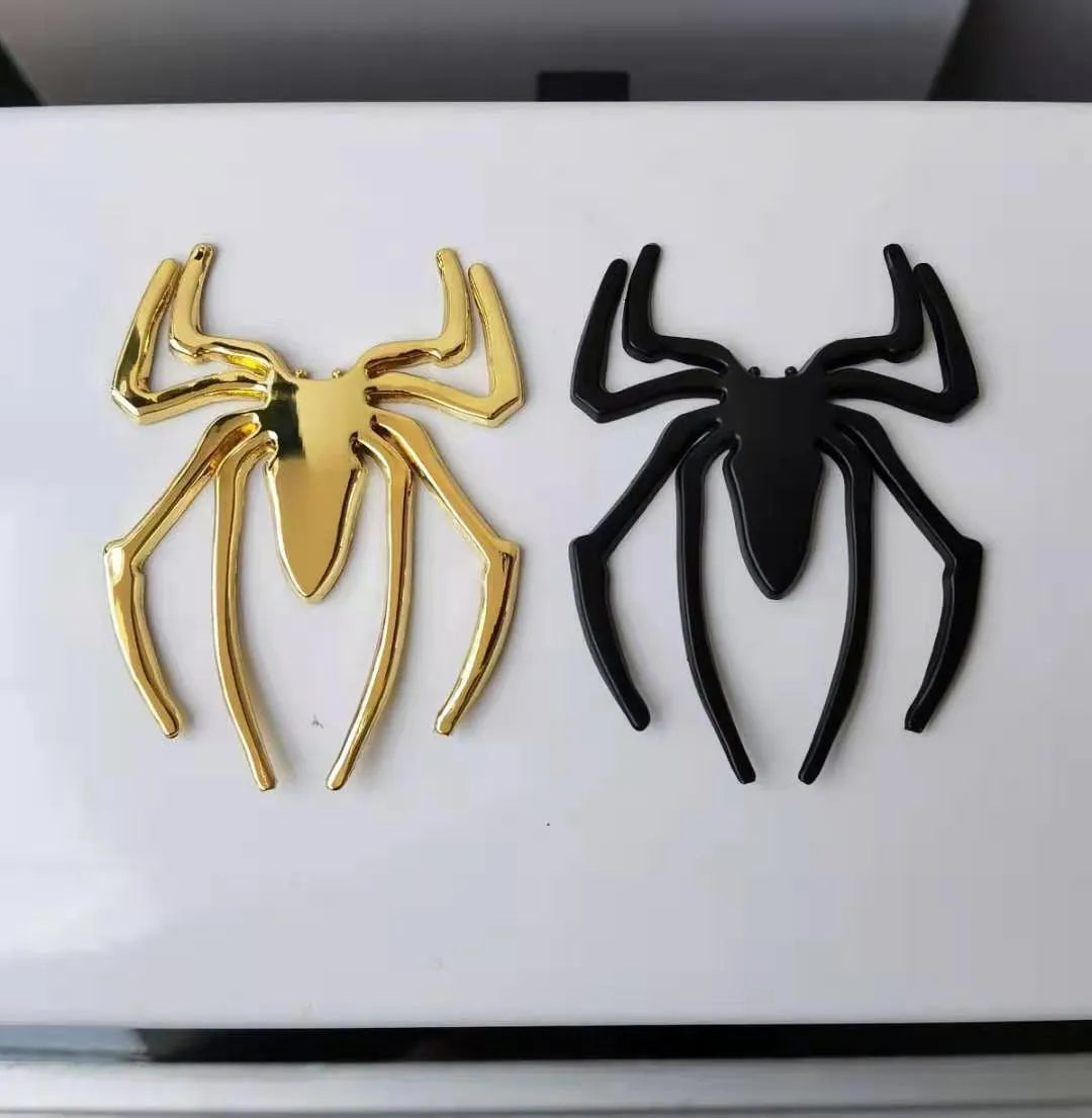 Three-dimensional metal spider bumper sticker in zinc alloy, shown in gold colour, measuring 7 by 5 cm.