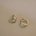 A pair of smooth sterling silver fishtail hoop earrings with a gold plated finish.