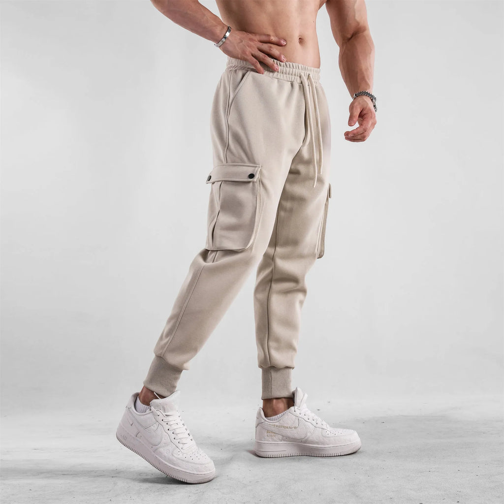 Men's loose grey cotton sports trousers with ankle ties and side pockets laid flat.