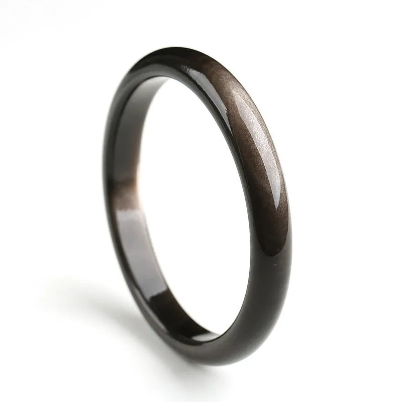 Ethnic geometric obsidian cat's eye bracelet in silver stone colours on a wrist.