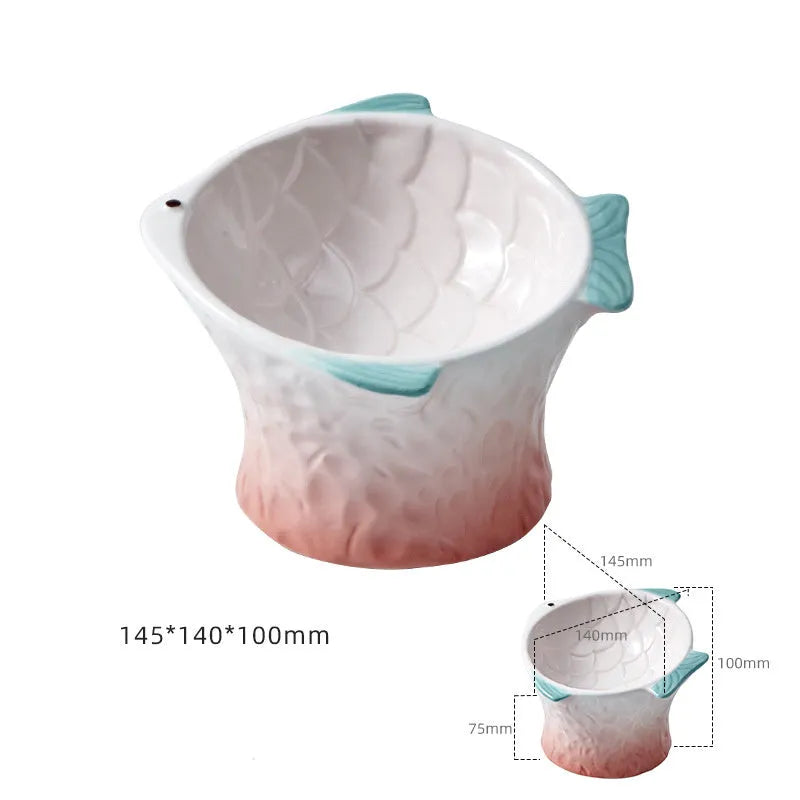 Set of four coloured fish-shaped ceramic cat bowls with elevated tilt design on a table.