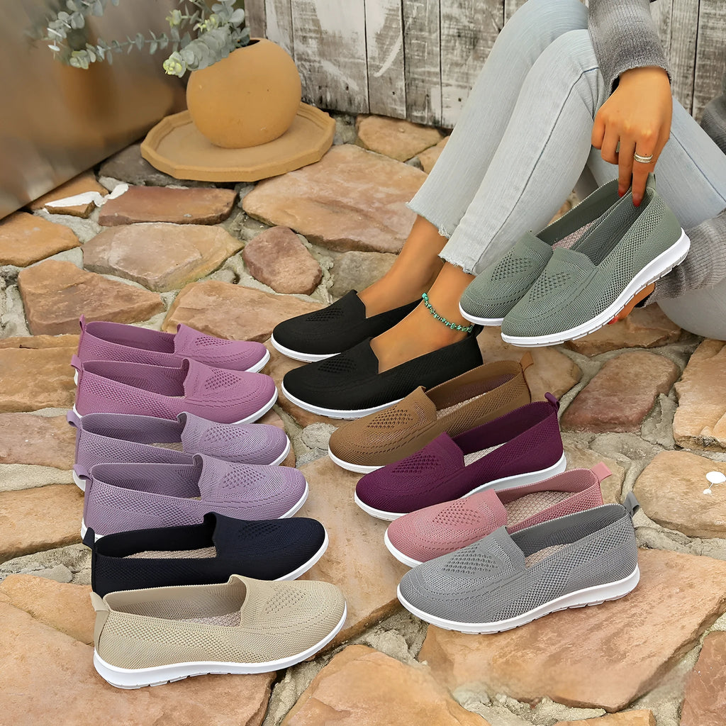 Women's beige canvas slip-on shoe with heart-shaped perforations and a flat sole.