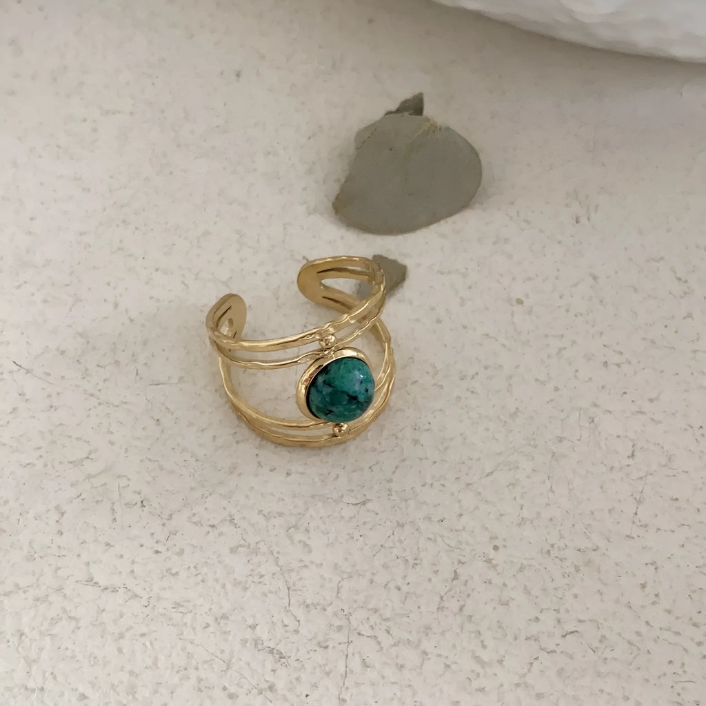 Geometric titanium steel open ring with a central natural green stone on a hand.