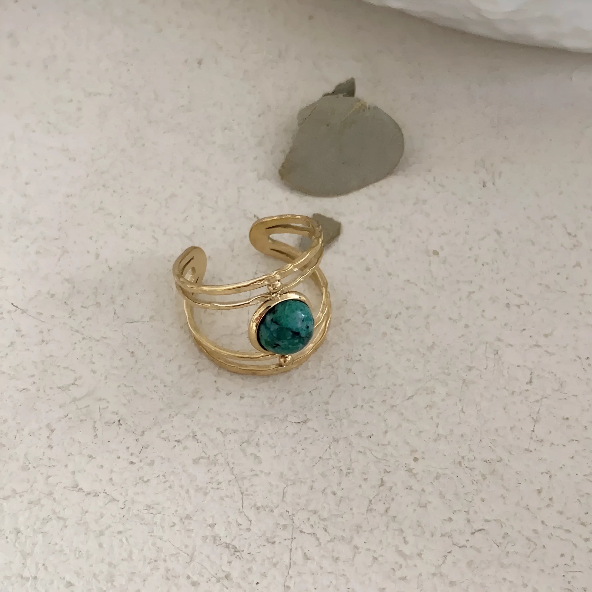 Geometric titanium steel open ring with a central natural green stone on a hand.