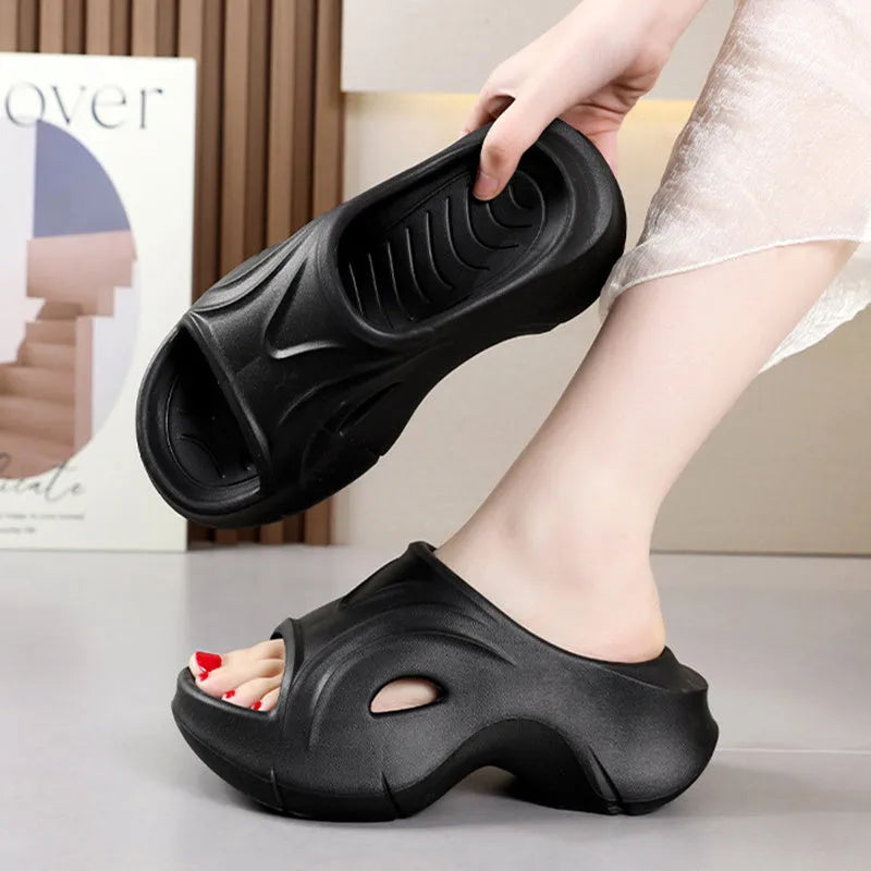 Women's white thick-soled EVA foam slippers with rounded toe on a beach.