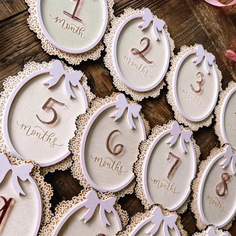 Carved boxwood lace frame bow baby milestone card with ten number stickers on a white background