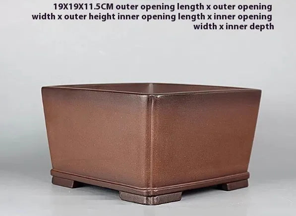 Brown handmade antique flower pot made from purple clay on a windowsill.