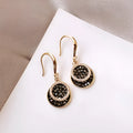 Black geometric alloy earrings with round piece shape measuring 3.6cm in length.