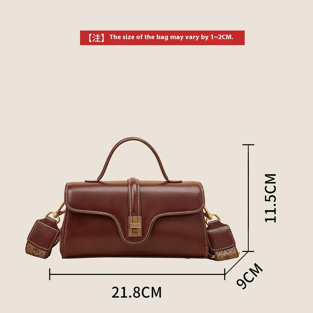 Brown Cambridge-style crossbody messenger bag with clamshell opening and lock detail on a table.