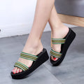 Women's brown bohemian wedge slippers with elastic strap on a wooden floor.
