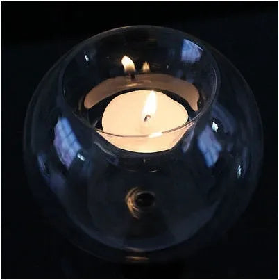 Handmade round hollow blown glass candle cup on a table.
