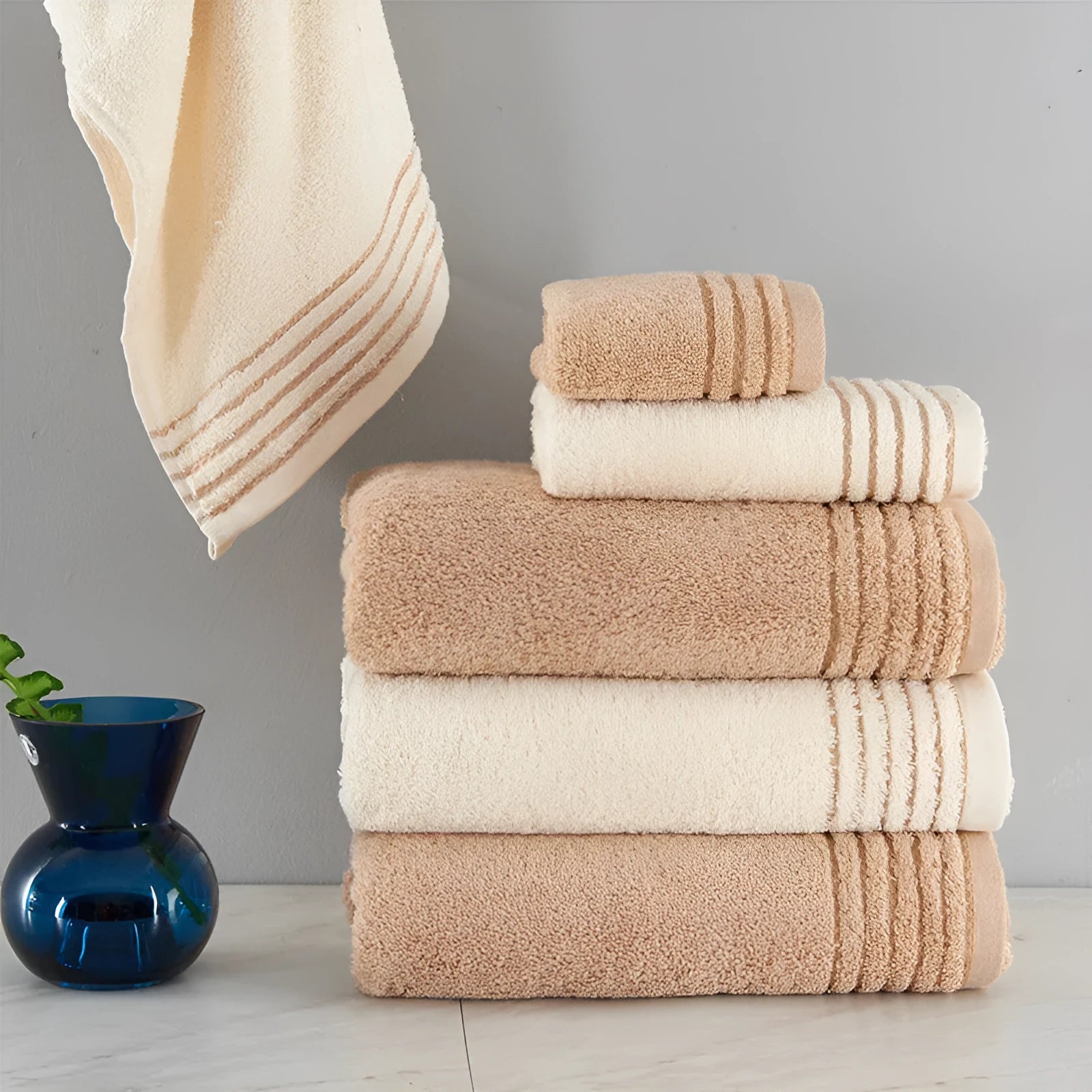 Beige and brown cotton bath towel set showing large bath towel, hand towel, and small face cloth.