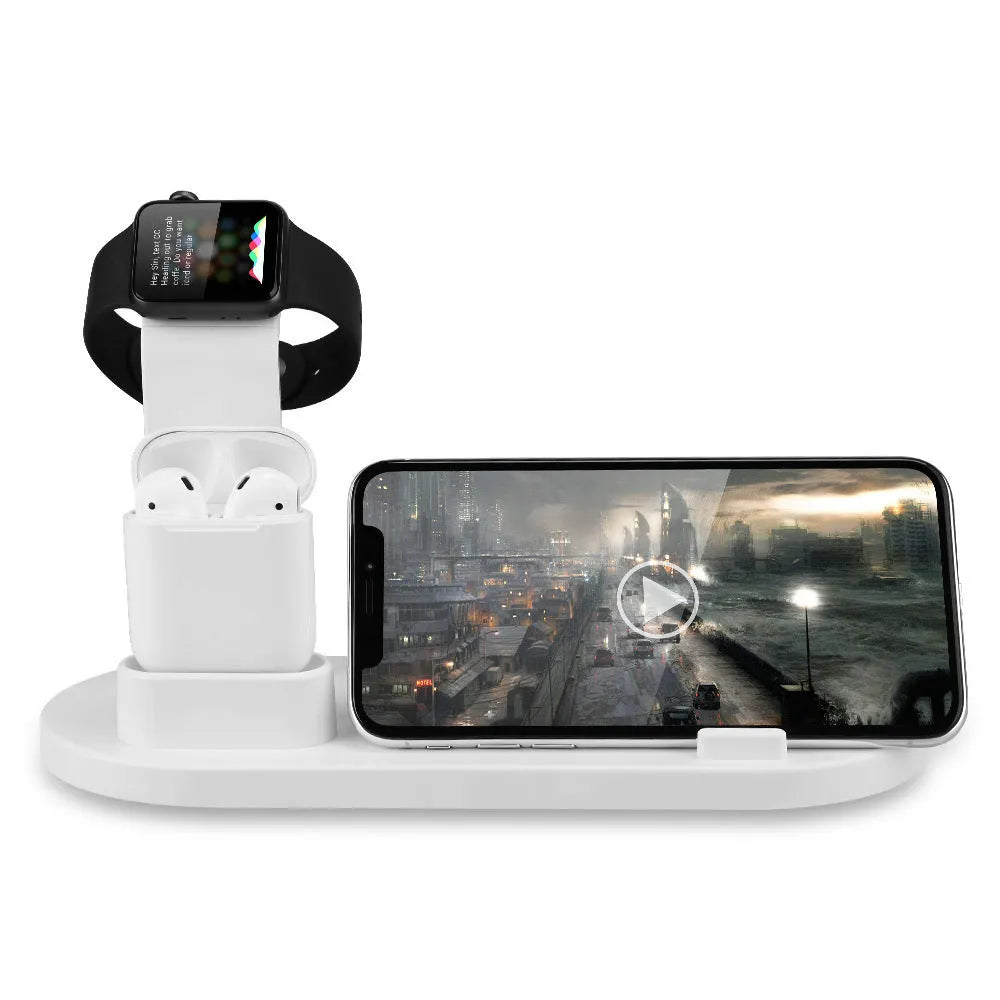 White three-in-one headphone charging stand dock on a desk with a USB cable.