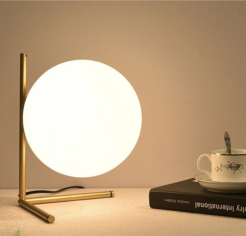 Creative glass desk lamp with three-tone LED lighting on a wooden desk.