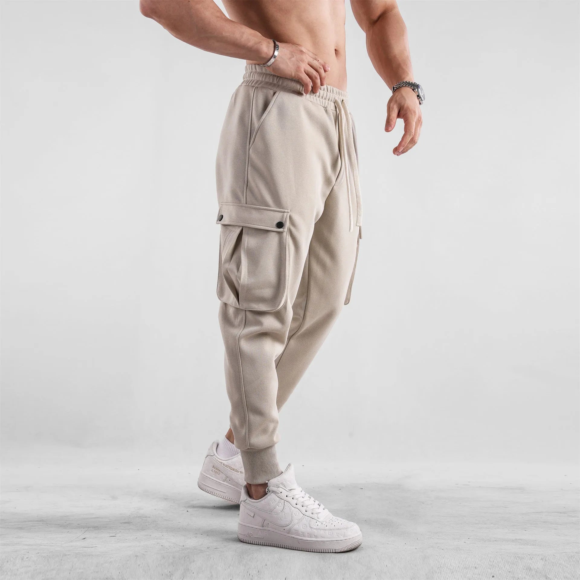 Men's loose grey cotton sports trousers with ankle ties and side pockets laid flat.