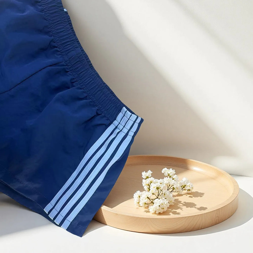 Men's navy blue high-waist nylon sports shorts laid flat, showing casual style and micro-elastic fabric.