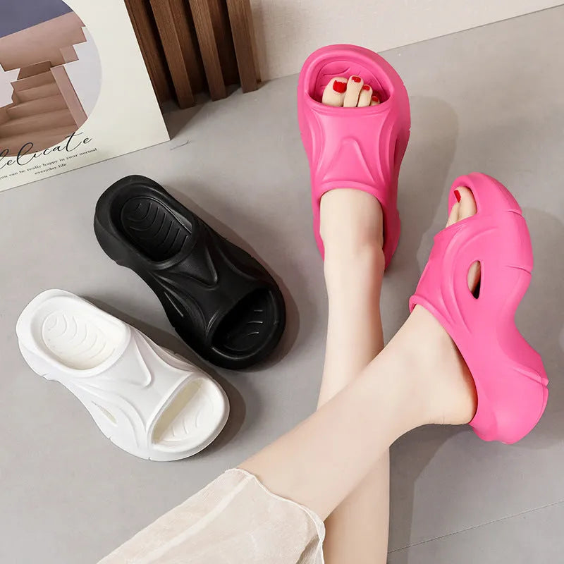 Women's white thick-soled EVA foam slippers with rounded toe on a beach.