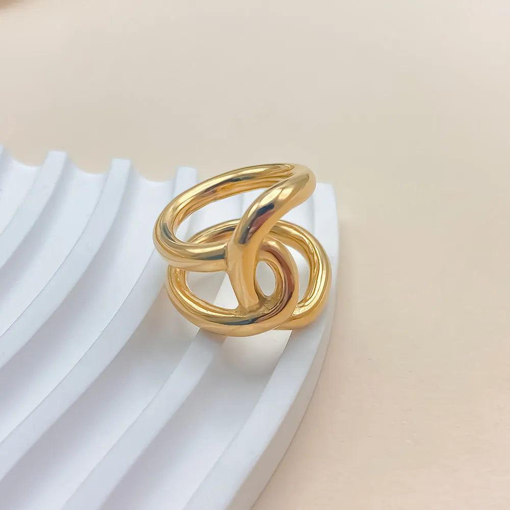 Women's stainless steel adjustable knotted open ring in gold or steel colour on a grey background.