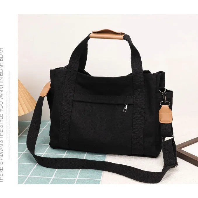 Khaki canvas tote bag with zipper closure showing internal camera pocket and document bag compartments.