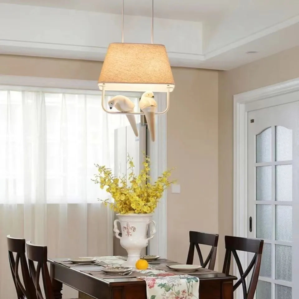 Iron ceiling chandelier with fabric shades featuring bird designs, hanging as a droplight.