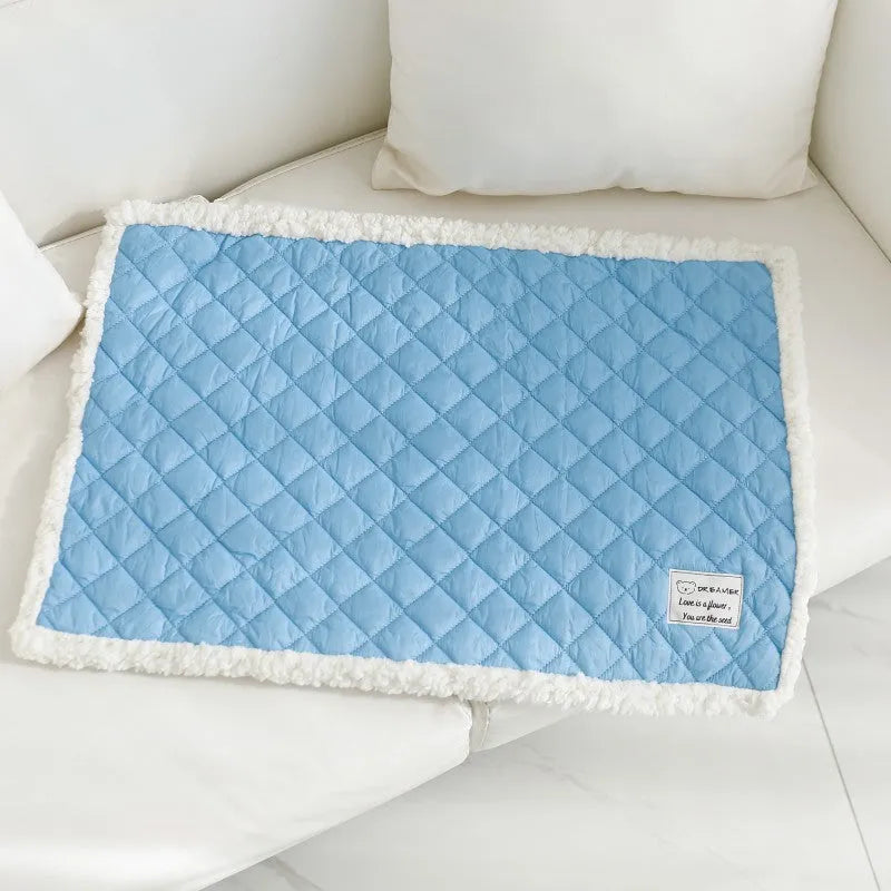 Quilted blue terry cloth pet blanket for cats on a white background, showing size scale.
