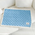 Quilted blue terry cloth pet blanket for cats on a white background, showing size scale.
