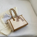 Soft PU leather square tote shoulder bag in black showing open outer pocket and internal phone compartment.