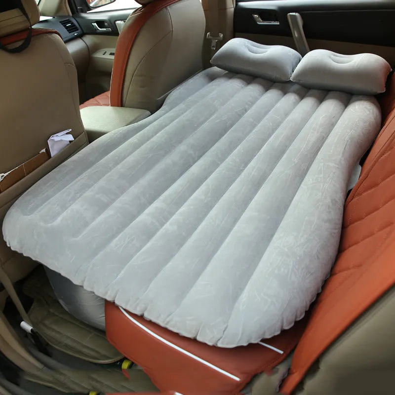 Black inflated car bed with flocked surface and two pillows inside a five-seater vehicle.