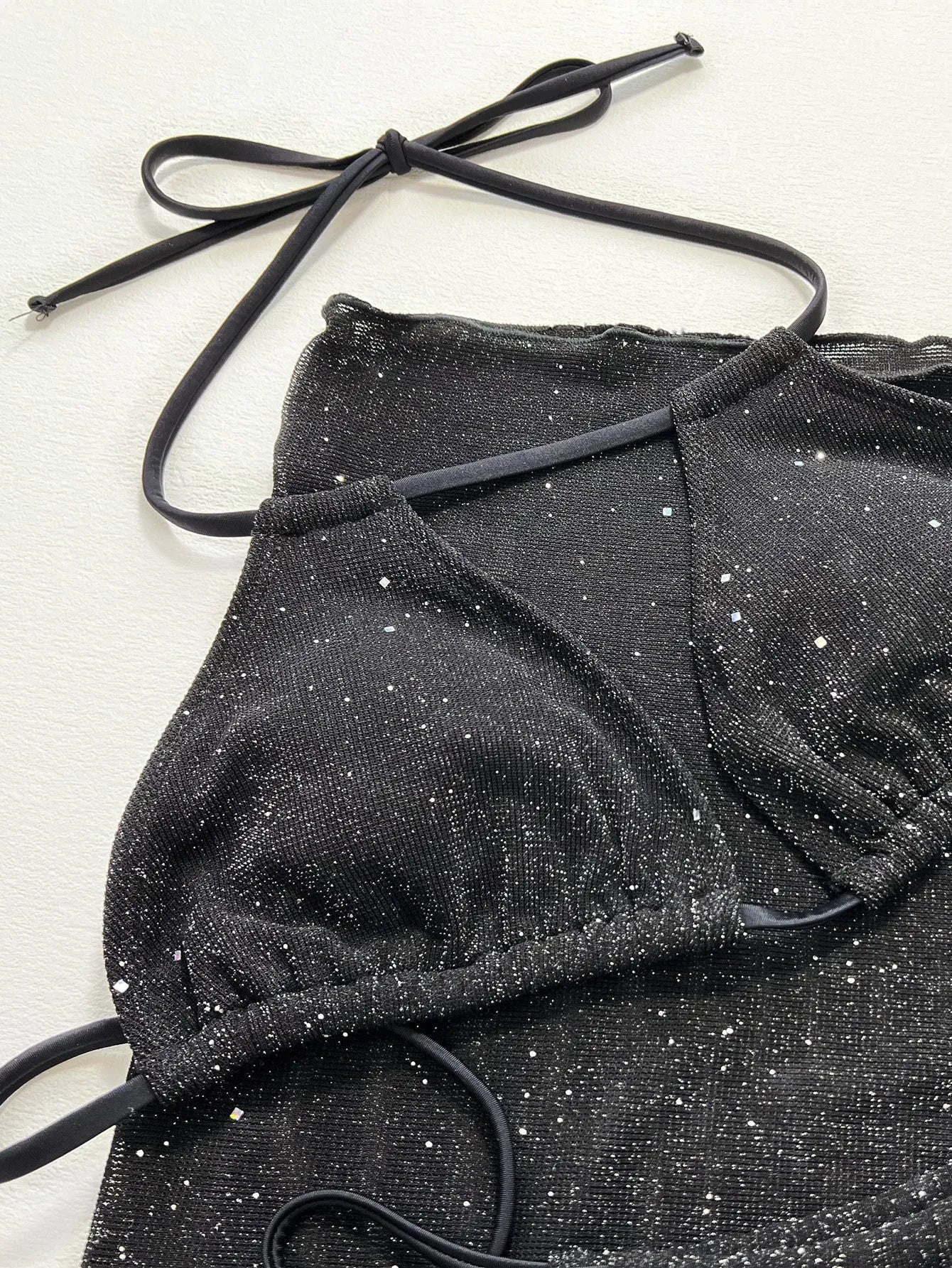 Black women's three-piece bikini swimsuit set with halterneck top and shorts on a mannequin.