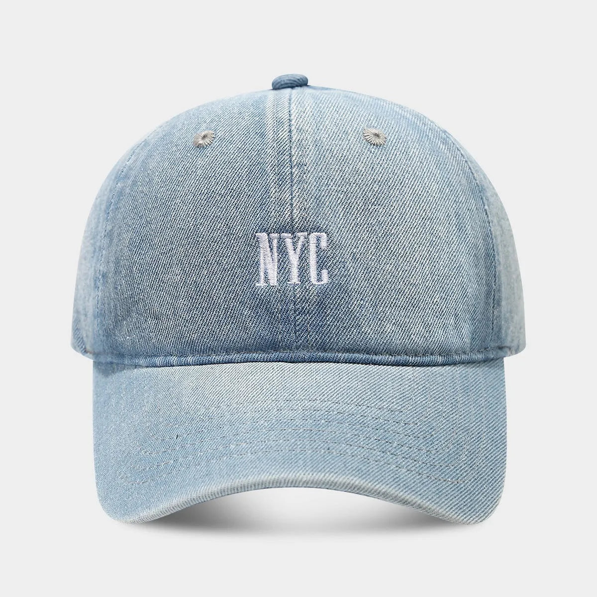 Light blue denim peaked cap with embroidered lettering on the front, showing adjustable strap.