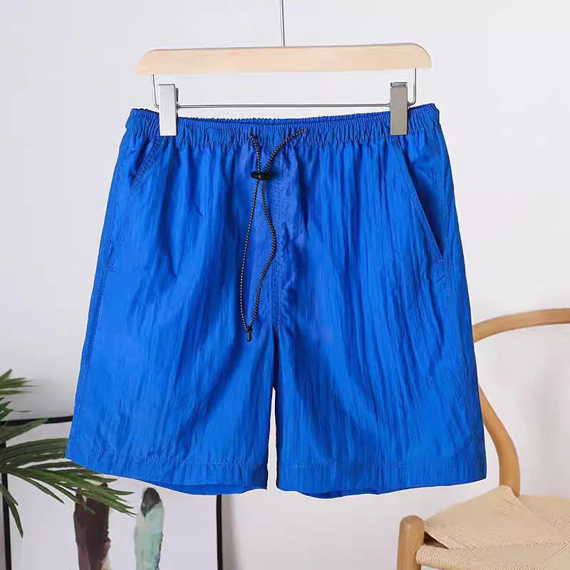 Man wearing straight-cut quick-dry sports shorts in grey, showing the thin polyester fabric and casual fit.