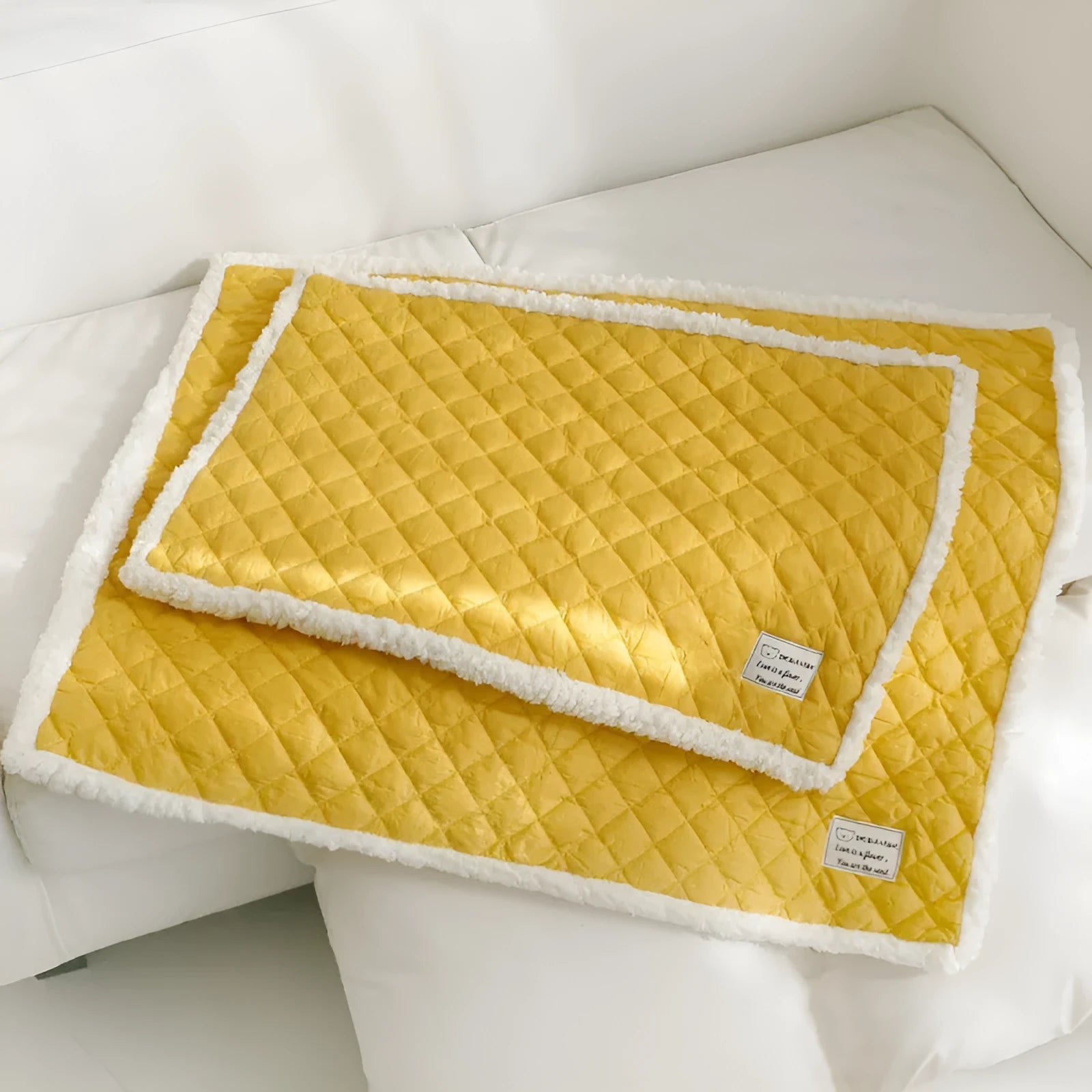 Quilted blue terry cloth pet blanket for cats on a white background, showing size scale.