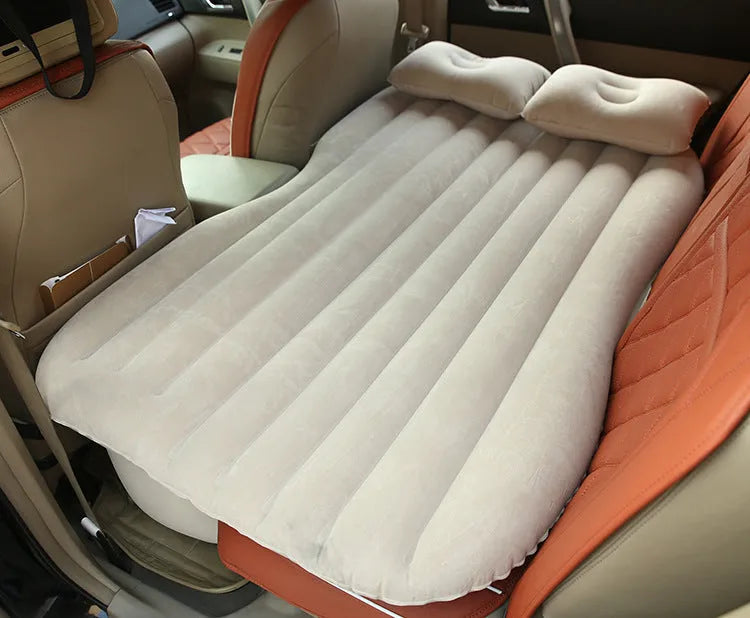 Black inflated car bed with flocked surface and two pillows inside a five-seater vehicle.