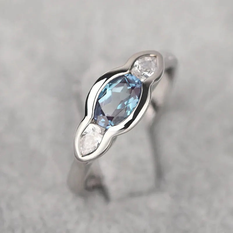 Geometric ellipse-shaped ring in white gold colour with zircon inlay, shown on a hand.