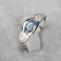 Geometric ellipse-shaped ring in white gold colour with zircon inlay, shown on a hand.