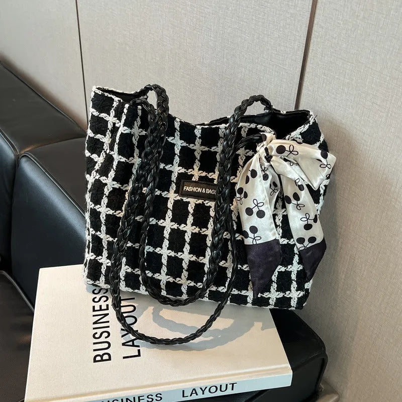 A black woven wool horizontal square shoulder bag showing external sandwich pocket and internal organiser compartments.
